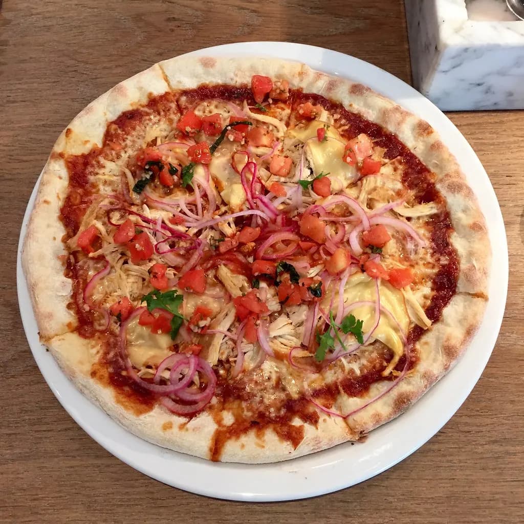 A pizza topped with chicken and red onion